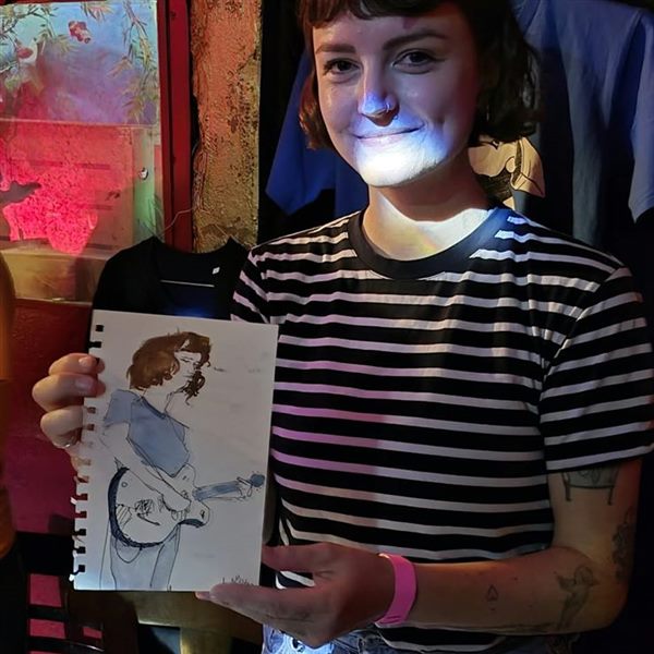 A musician holding her live-drawn portrait